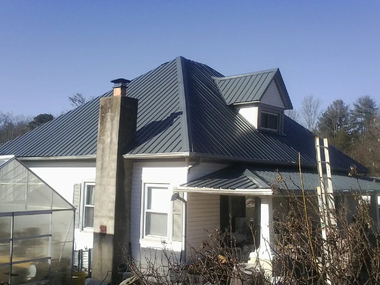 Dark blue standing seam metal roof on a white farmhouse with dormer — Slate & Tile Roof Repair by Roofing Brothers in Ada