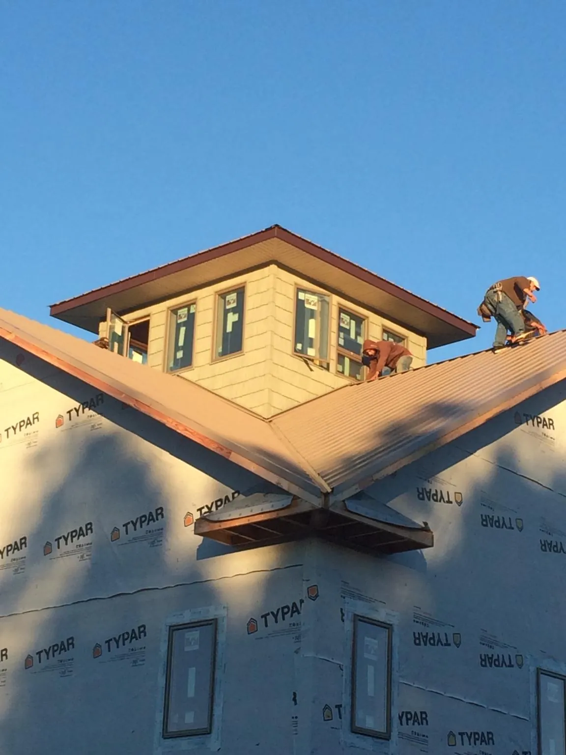 Roofers working around a rooftop cupola on a new metal roof at sunset — Roof Waterproofing in Ada by Roofing Brothers